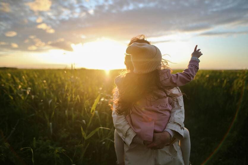 Madre e hija abrazadas viendo una puesta de sol
